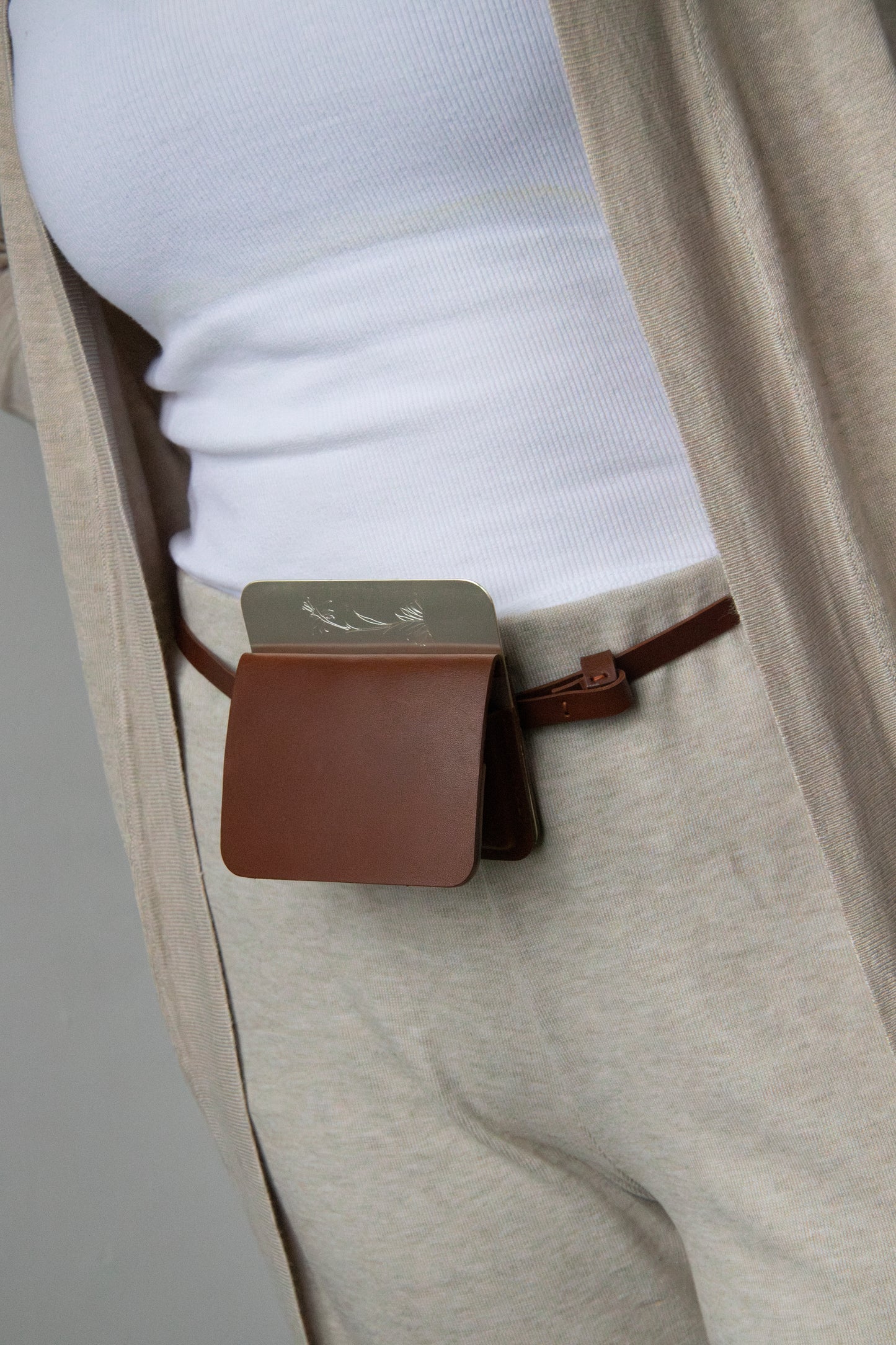 silver/brown flap belt bag with signature of Levnî