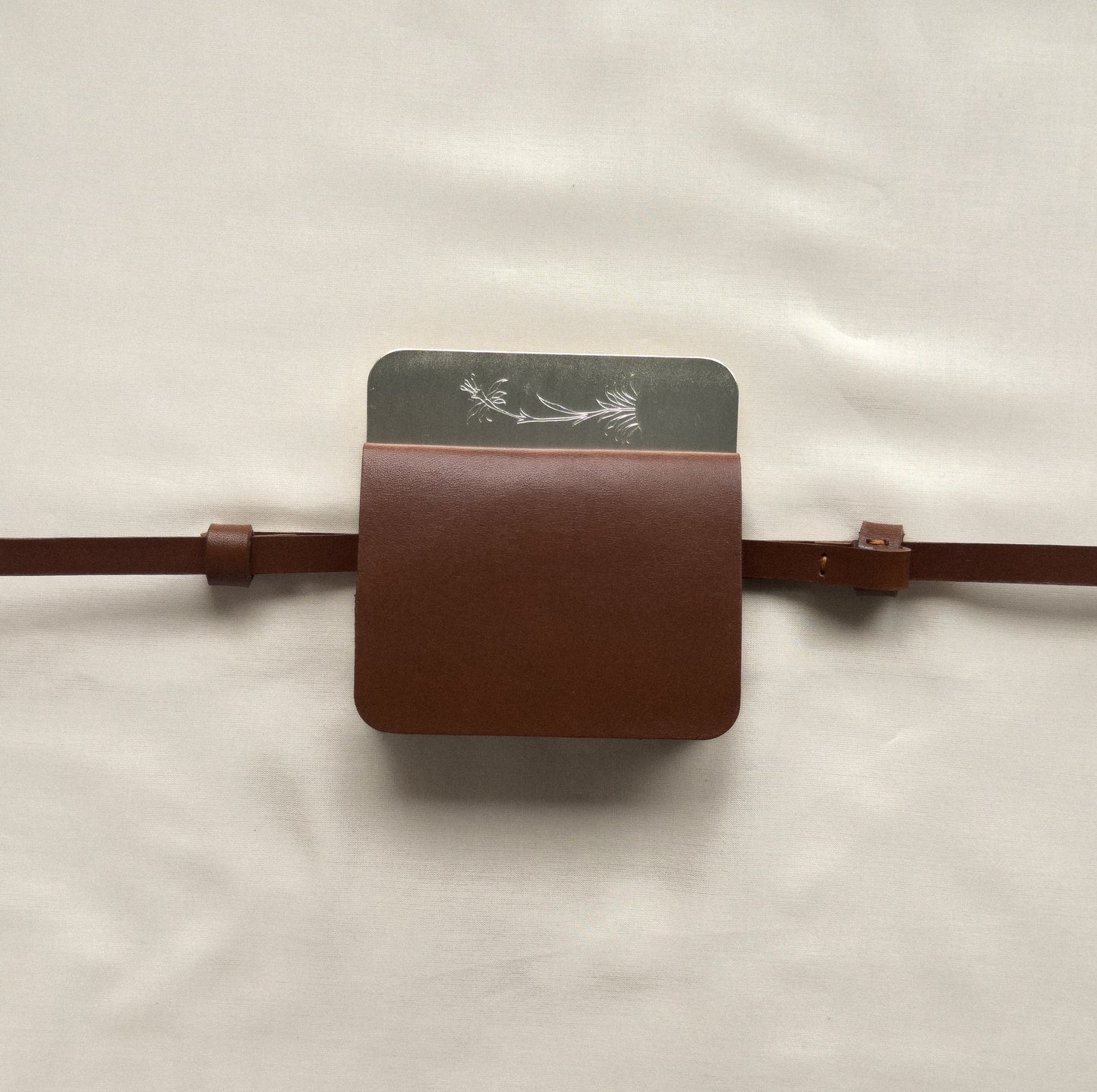 silver/brown flap belt bag with signature of Levnî
